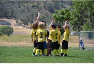 Little kids soccer team high fiving on soccer field. 